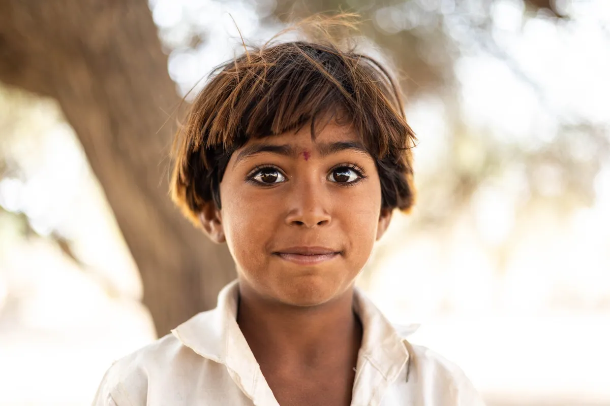 Desert child. During a camel journey in the state of Rajasthan, some children from a nearby village were playing at a well that we had stopped at to let the camels drink. Despite being unable to communicate via speech due to our language barriers, we managed to work out names and ages using a game of charades, and drawing lines in the earth. We climbed trees and they picked edible berries for us to snack on. They were all extremely photogenic, but this was my favourite shot of the series. Desert nr. Jaisalmer, India